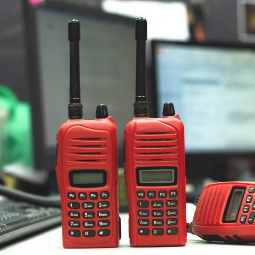 Red Walkie-talkie radio on wooden table operator in office.